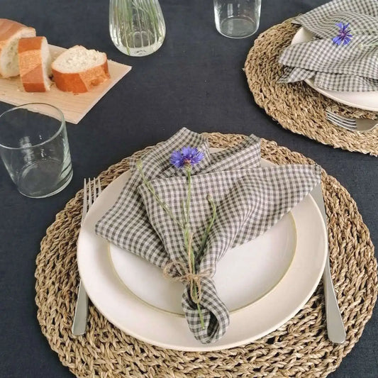 Eine karierte Leinenserviette aus Litauen mit einer  Kornblume auf einem Teller