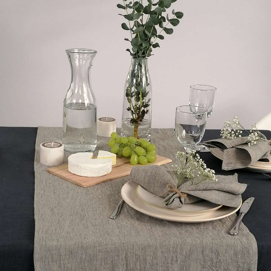 Tischläufer aus Leinen mit feinen grauen Streifen auf tisch mit grauer Tischdecke und Gedeck